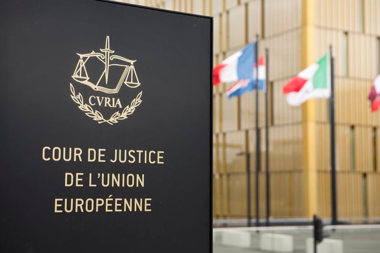 Sign saying "Cour de Justice de l'Union Européenne" outside the Court of Justice of the European Union in Luxembourg. Flags in the background.