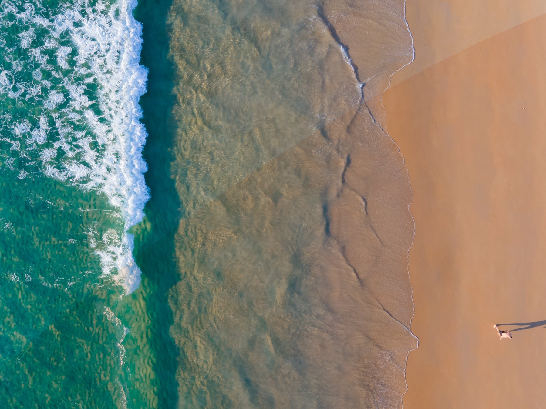 Aerial top-down view of a sand beach meeting the sea.