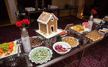 A Christmas dessert table with a gingerbread house centerpiece, chocolates, and candy.