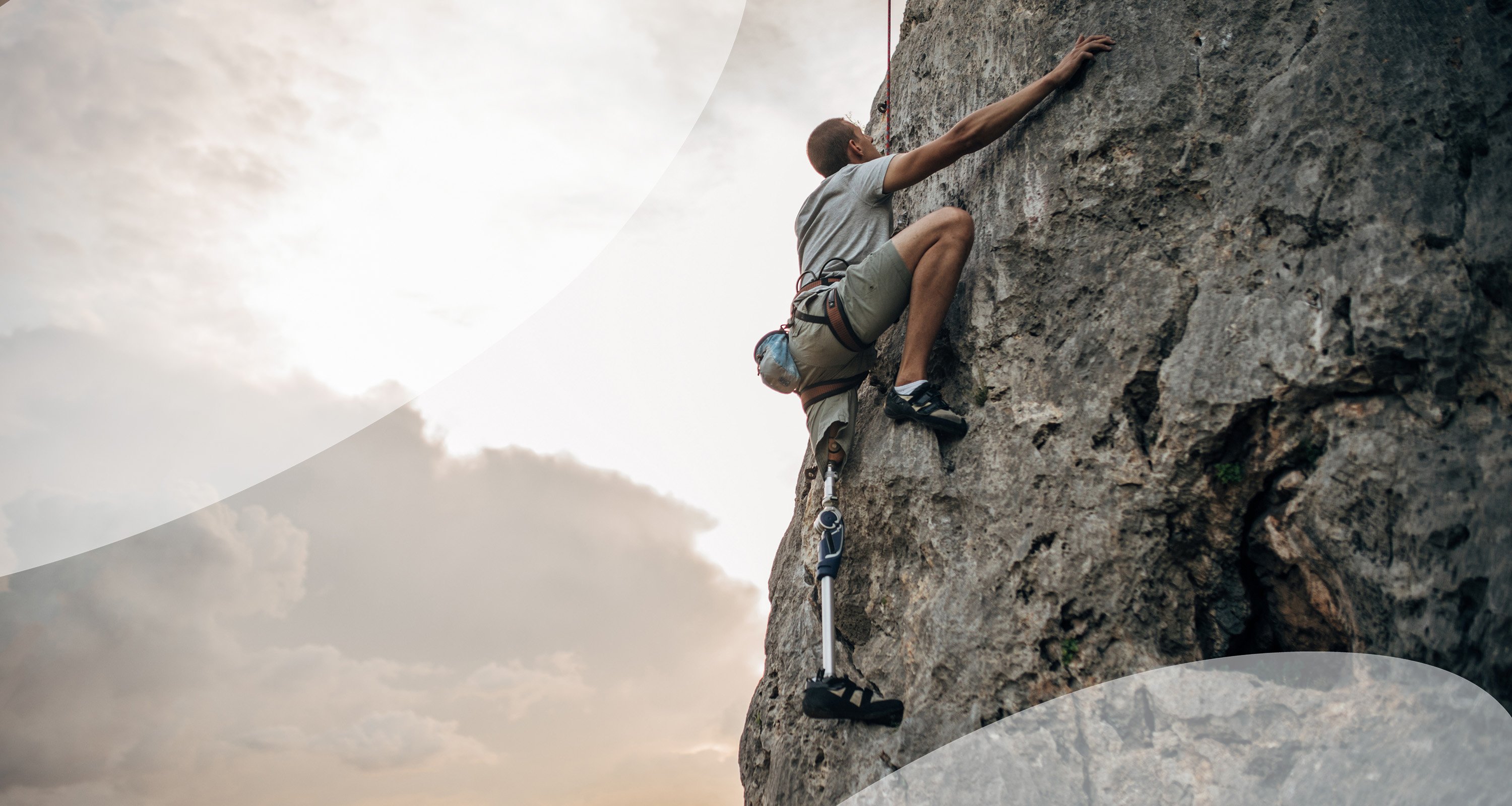 A man with a prosthetic leg is free-climbing.